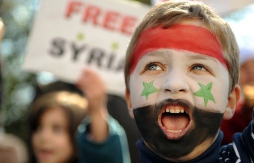 picture showing a child, shouting, with the syrian colors in his face